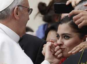 Woman kisses Pope Francis' hand as he greets guests during general audience in St. Peter's Square at Vatican