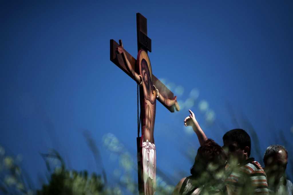 People followers of the Greek Orthodox Church stand in front of an image of Jesus crucified during the ceremony marking the Apokathelosis